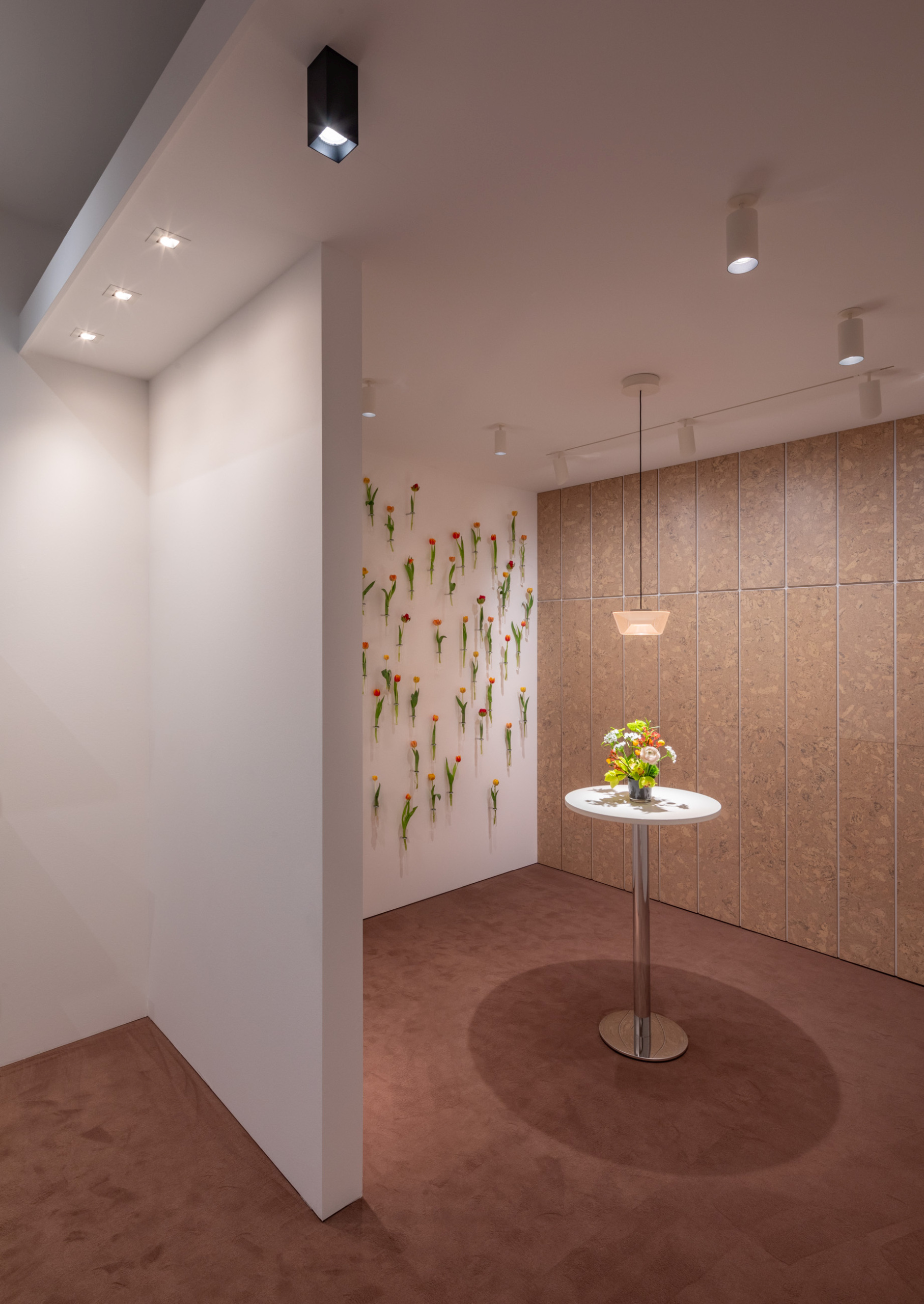 Detail eines Messestands mit Blütenwand, Naturtönen und gezielter Beleuchtung